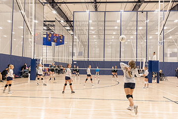 Inside of AtTheGrounds sports arena with kids playing volleyball
